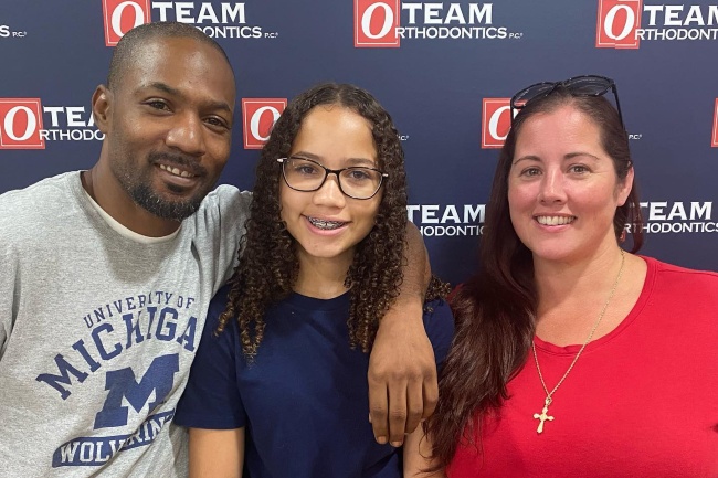 Whole family of patients of Team Orthodontics smile for a photo.