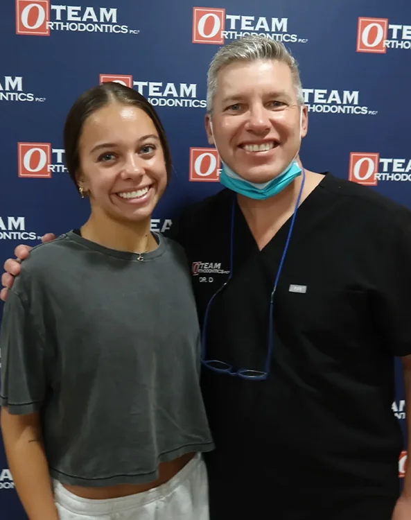 Patient posing with the Team Orthodontics orthodontist after completing orthodontic treatment.